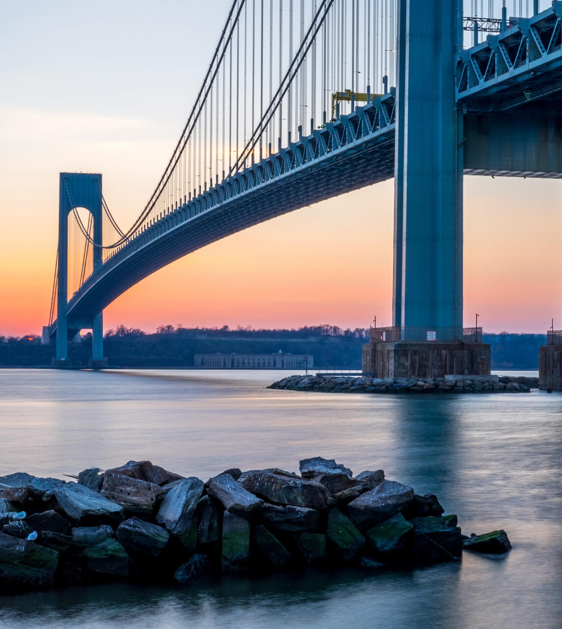 Suspension bridge over river with rocks in the foreground